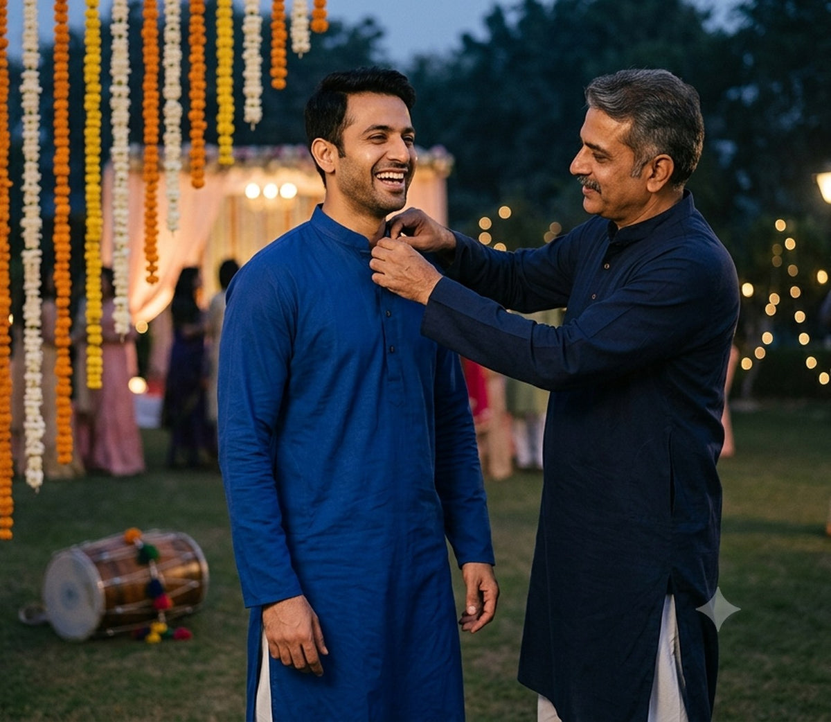 A father straightening his son's royal blue kurta collar at a wedding sangeet